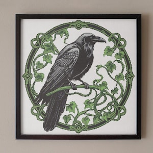 May include: A black raven perched on a branch of green ivy, surrounded by a circular frame with intricate details. The raven is facing right and has a detailed design.