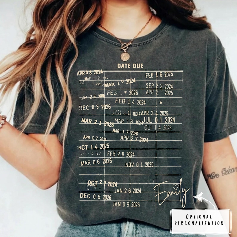 May include: Dark gray t-shirt with a printed chart design featuring dates and the text "DATE DUE." The shirt includes the name "Emily" in cursive and the words "OPTIONAL PERSONALIZATION" in a white box.