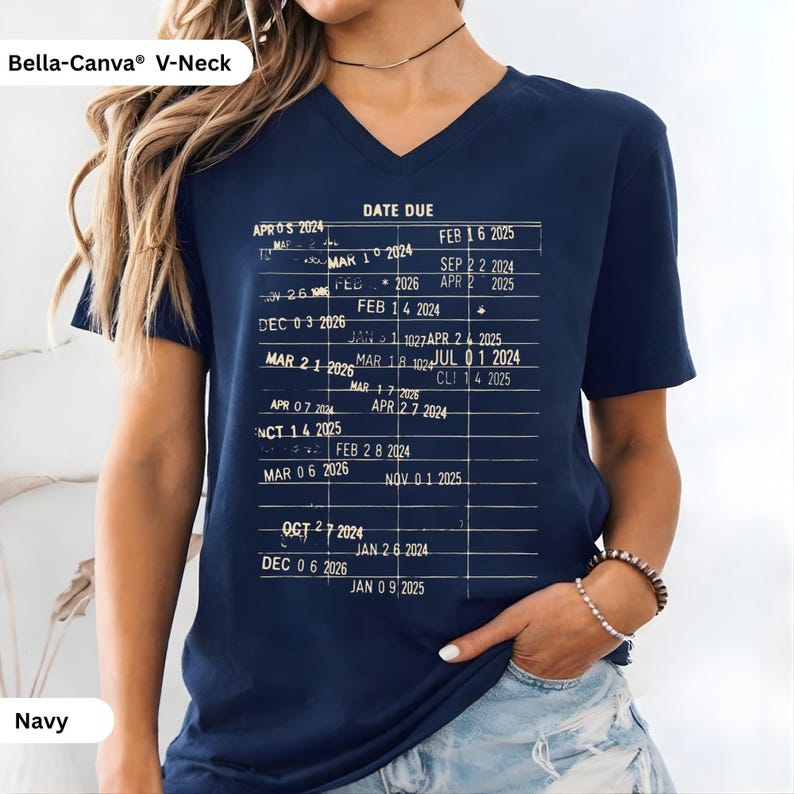 May include: Navy blue V-neck t-shirt with a vintage library card design printed on the front. The graphic includes the words "DATE DUE" and various dates. The shirt is made of a soft material and is labeled "Bella-Canva&reg; V-Neck".