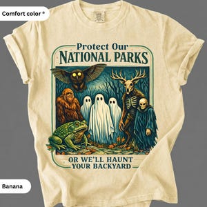 May include: Banana-colored Comfort Colors t-shirt with a graphic that reads "Protect Our National Parks OR WE'LL HAUNT YOUR BACKYARD." The graphic features a variety of cryptids and spooky creatures.