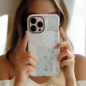 May include: A white iPhone case with a blue and white patchwork design. The case has a camera lens cutout and a white background.