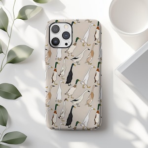 May include: A phone case featuring a repeating pattern of stylized ducks in various colors, including white, black, and brown, set against a beige background. The case has a glossy finish and a camera cutout.