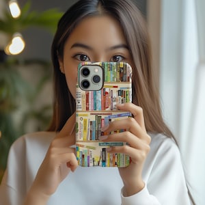 May include: A smartphone case featuring a colorful bookshelf design. The case displays rows of books with various spine colors and titles. The case is held up in front of a person's face.