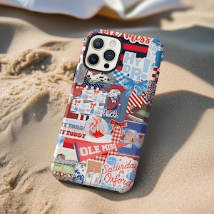 May include: A colorful phone case with a collage design featuring the text "Ole Miss", "Saturday in Oxford", and "Hy PR!". The case has a mix of red, white, and blue patterns, bows, and illustrations. The case is lying on a sandy surface.