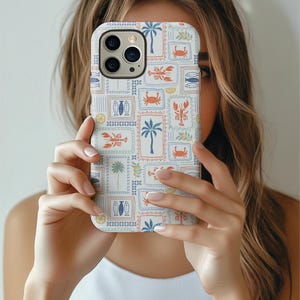 May include: A white phone case featuring a repeating pattern of postage stamp-style illustrations. The stamps depict palm trees, crabs, lobsters, fish, and lemons in shades of blue, orange, and green. The case has a glossy finish and a camera cutout.