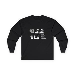 May include: Black long-sleeve shirt with a white graphic featuring anime-style eyes and text. The text reads "The world is merciless, and it's also very beautiful" and a quote about changing yourself.