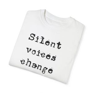 May include: White t-shirt with the text "Silent voices change" printed in black typewriter font.