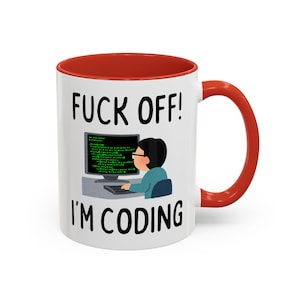 Może przedstawiać: Biały ceramiczny kubek z czerwonym wnętrzem i uchwytem. Kubek zawiera czarny napis "FUCK OFF! I'M CODING" z ilustracją osoby kodującej na komputerze.