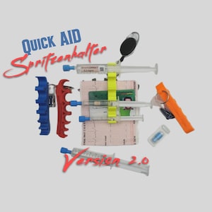 Könnte beinhalten: Eine Ansammlung medizinischer Geräte, darunter Spritzen, ein Schlüsselanhänger und ein kleiner Spiegel, wird vor einem hellen Hintergrund gezeigt. Der Text "QUICK AID Spritzenhalter Version 2.0" ist in Blau und Rot zu sehen.