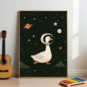 May include: A rectangular wall art print featuring a white goose wearing a glass astronaut helmet. The background is a dark green space scene with an orange ringed planet, a smiling moon, and various white and orange stars scattered throughout.