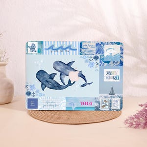 May include: A light blue laptop skin featuring two whales with a watercolor effect. The design includes various nautical elements, such as waves, anchors, and seashells. Text includes "do what you love", "go with the flow", "East Coast", and "YOLO".