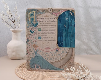 May include: A decorative wooden plaque featuring a quote from a fairy tale. The plaque has a light beige background with floral and bird designs. The text "dream is a wish your heart makes" is displayed with an illustration of a princess and a castle.