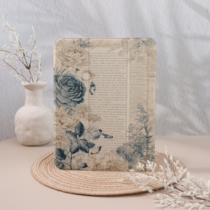 May include: Tablet case with a floral design featuring blue and cream roses, butterflies, and botanical elements. The case has a vintage newspaper print background and a neutral colour palette.