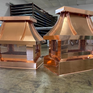 Puede incluir: Dos sombreros de chimenea de cobre con base rectangular, pantalla de malla y parte superior de varios niveles estilo pagoda. Las tapas tienen una superficie brillante y reflectante.