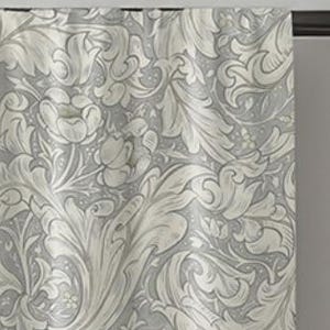 May include: A gray curtain with a repeating floral pattern in shades of white and light gray. The design features stylized leaves and flowers, creating a classic, elegant look. The curtain is hanging from a dark rod.