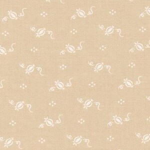 May include: Tan fabric with a repeating pattern of white floral and dot designs. The fabric has a textured appearance and is suitable for quilting or other craft projects. The pattern is evenly spaced across the fabric.