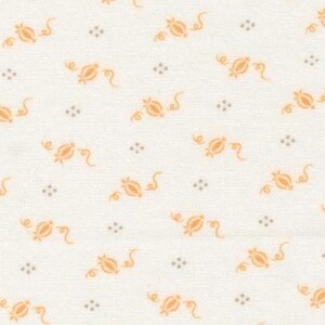 May include: Cream-colored fabric with a repeating pattern of orange floral designs and small gray dots. The fabric has a ruler along the bottom edge, indicating measurements in inches. This textile is suitable for quilting or crafting projects.