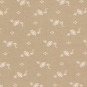 May include: Tan fabric with a repeating pattern of small white floral and dot designs. The fabric has a textured appearance and is suitable for quilting or other craft projects. The pattern is evenly spaced across the fabric.