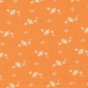 May include: Orange fabric with a repeating pattern of white floral and dot designs. The fabric has a textured appearance and is suitable for quilting or other craft projects. The design is a classic, vintage style.