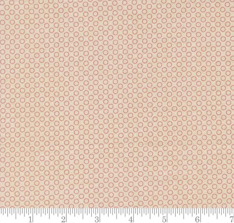 May include: A beige fabric with a repeating pattern of small, red circles. The circles are evenly spaced across the fabric's surface. The fabric has a subtle texture and a ruler is at the bottom.