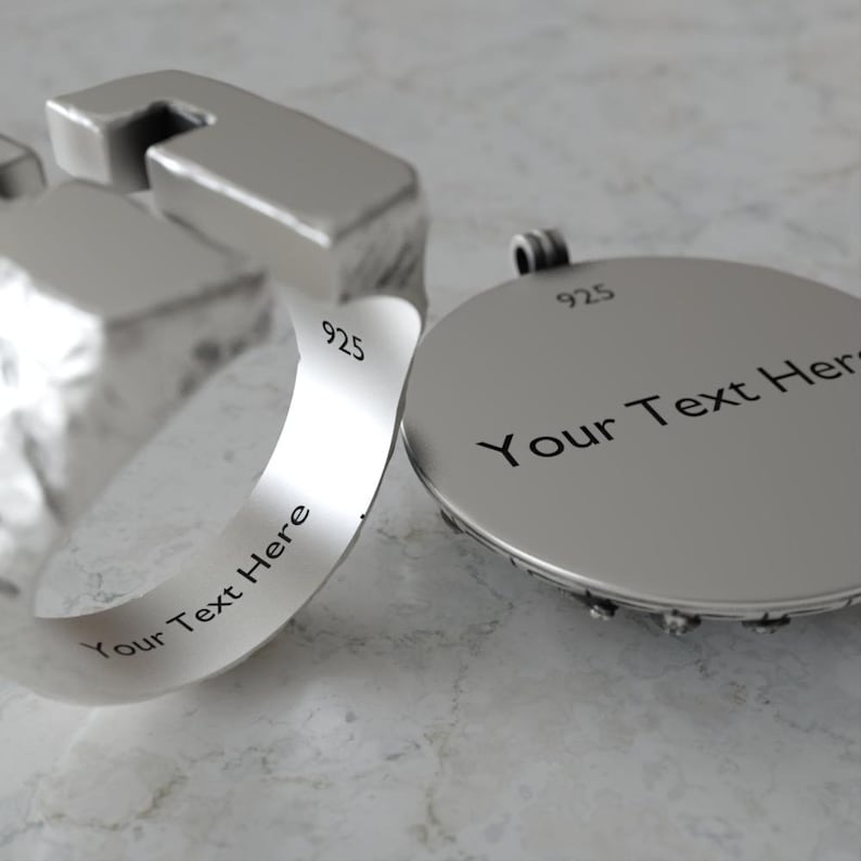 May include: A close-up of a silver ring and pendant. The ring has a unique geometric design with the text "Your Text Here" engraved on the band. The pendant is round with the text "Your Text Here" and the number "925" engraved on it.