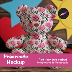May include: A pink teddy bear with a floral pattern. The pattern features pink flowers and green leaves on a white background. The teddy bear is sitting on a wooden surface. Procreate Mockup. Add your own design! Only works in Procreate.