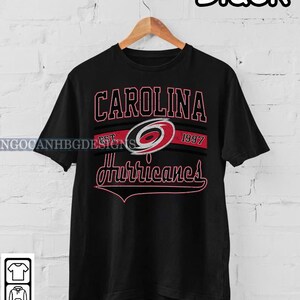 May include: Black t-shirt with a Carolina Hurricanes logo and the text "Carolina Est. 1997 Hurricanes".