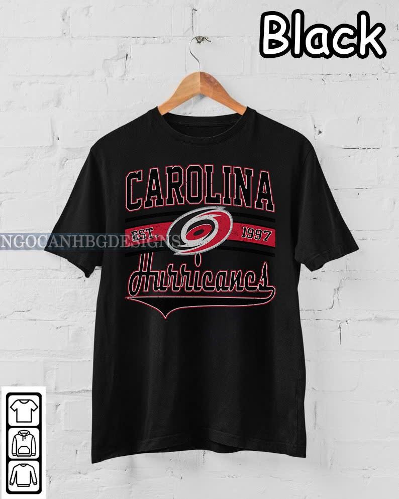 May include: Black t-shirt with a Carolina Hurricanes logo and the text "Carolina Est. 1997 Hurricanes".