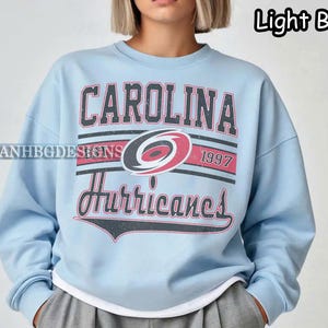 May include: Light blue sweatshirt with a Carolina Hurricanes logo and the text "Carolina Hurricanes 1997".