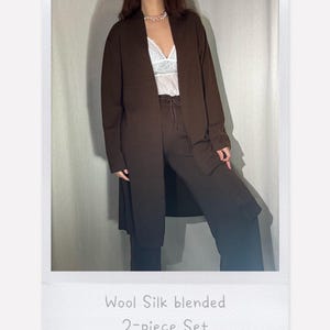 May include: A brown wool and silk blend two-piece set. The set features a long, open-front cardigan and matching trousers. The image is framed in a white border, with the text "Wool Silk blended 2-piece Set" at the bottom.