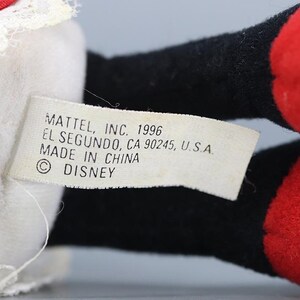 May include: Close-up of a vintage Disney plush toy. The toy features black, red, and white elements. A tag reads "MATTEL, INC. 1996 EL SEGUNDO, CA 90245, U.S.A. MADE IN CHINA &copy; DISNEY."