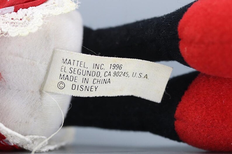 May include: Close-up of a vintage Disney plush toy. The toy features black, red, and white elements. A tag reads "MATTEL, INC. 1996 EL SEGUNDO, CA 90245, U.S.A. MADE IN CHINA &copy; DISNEY."