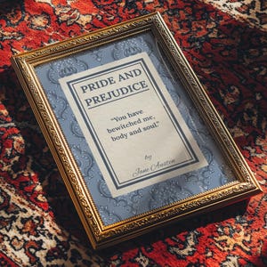 May include: A framed print of "Pride and Prejudice" by Jane Austen. The gold-colored frame surrounds a print with the book title and a quote: "You have bewitched me, body and soul." The background is a light blue floral pattern.