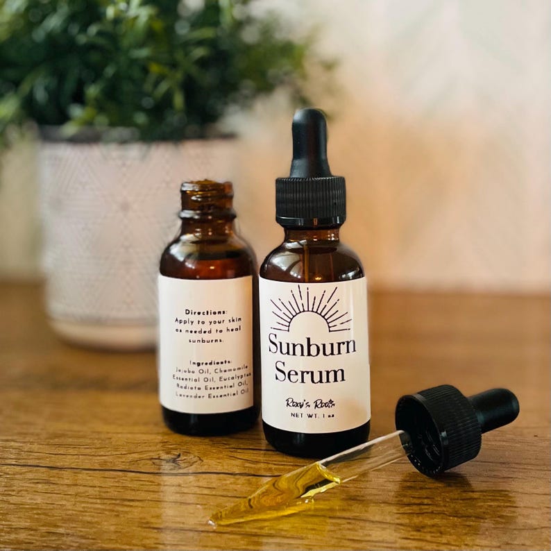 May include: Two brown glass bottles of Sunburn Serum with white labels and black droppers. One bottle has a dropper extended, dispensing the serum. The labels read "Sunburn Serum" and "Ray's Roots". The net weight is 1 fl oz.