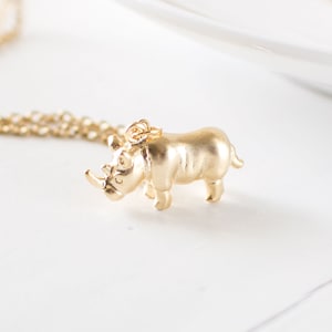 May include: A gold chain necklace with a small gold rhinoceros pendant.