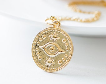 May include: Gold necklace with a round pendant featuring an eye with stars and a beaded border.