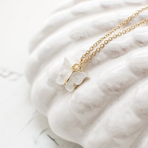 May include: A delicate gold chain necklace with a white sparkly butterfly pendant.
