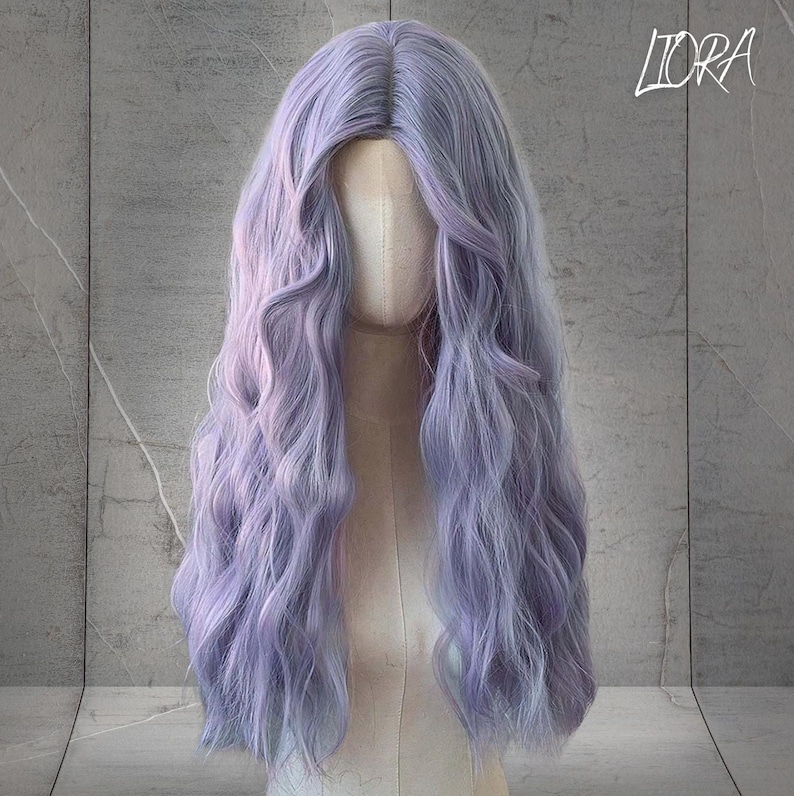 May include: A long, wavy wig in shades of lavender and light purple, displayed on a mannequin head. The wig has a natural-looking part and long, flowing curls. The text "LORA" is visible in the upper right corner.