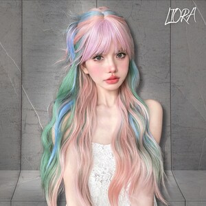 May include: A long, wavy wig with a pastel color scheme. The wig features a blend of pink, blue, and green hues, with a fringe and long, flowing strands. The word "LIORA" is written in cursive in the upper right corner.
