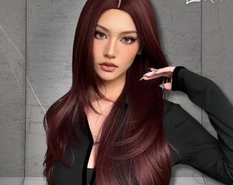 May include: A long, layered wig in a deep burgundy shade. The wig features a natural-looking part and flows down the shoulders. The image includes the text "LIORA" in the upper right corner. The person is wearing a black top.