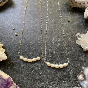 Puede incluir: Dos delicados collares con una fila de peque&ntilde;as perlas blancas. Uno es de oro y el otro de plata.