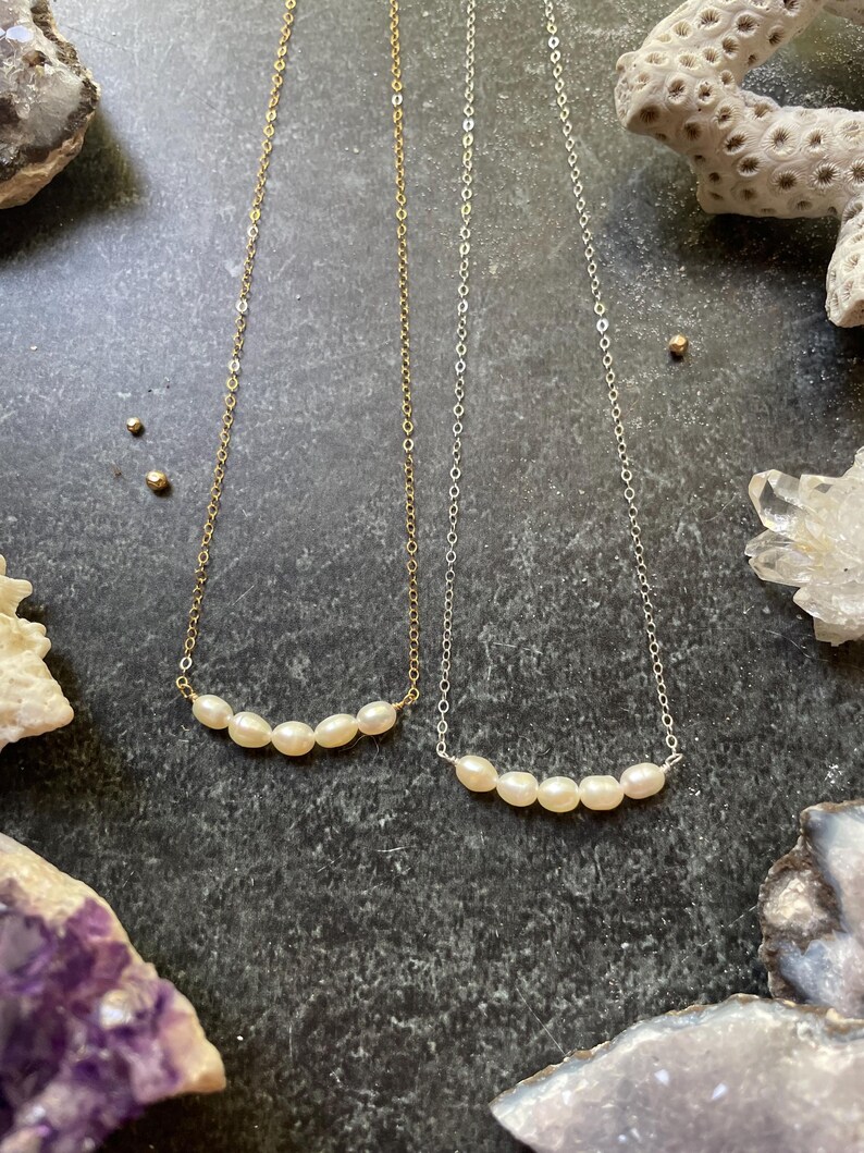 Puede incluir: Dos delicados collares con una fila de peque&ntilde;as perlas blancas. Uno es de oro y el otro de plata.
