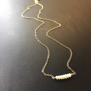 May include: A delicate gold chain necklace with a row of small white pearls.