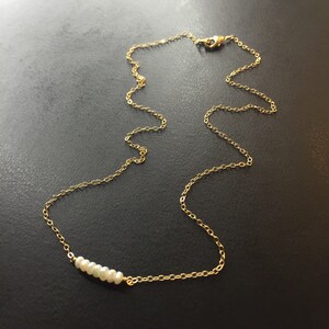 May include: A delicate gold chain necklace with a row of small white pearls.
