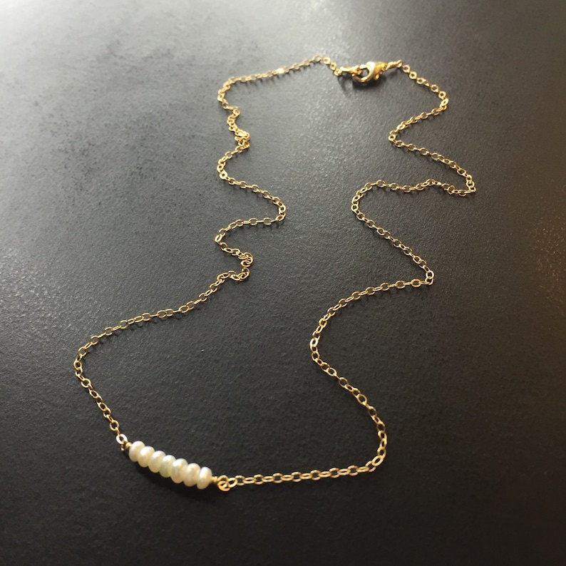 May include: A delicate gold chain necklace with a row of small white pearls.
