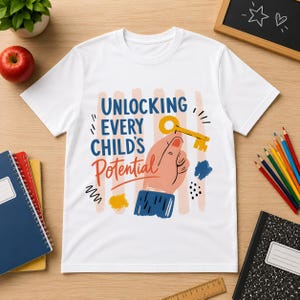 Può includere: Una t-shirt bianca a maniche corte con una stampa grafica che raffigura una mano che tiene una chiave gialla. Il testo "UNLOCKING EVERY CHILD'S POTENTIAL" è scritto in blu e arancione, accompagnato da forme astratte in blu, arancione e nero.
