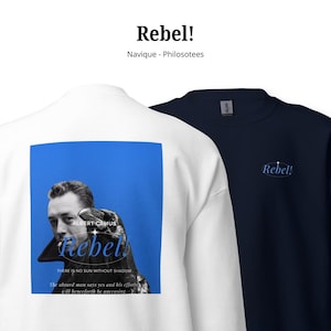 Könnte beinhalten: Ein weißes Sweatshirt mit einer großen blauen quadratischen Grafik auf der Rückseite, die ein schwarz-weißes Porträt von Albert Camus, einen Vogel und den Text Rebel! There is no sun without shadow. The absurd man says yes and his efforts will henceforth be unceasing zeigt. Ein marineblaues Sweatshirt mit dem Text Rebel! auf der Vorderseite.