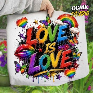 以下が含まれることがあります： LOVE IS LOVEという文字が描かれたカラフルなグラフィックが特徴の白い布製品。虹色の文字、蝶、ハート、星、虹のアーチ、唇がデザインされており、ペンキが飛び散ったようなエフェクトが施されています。