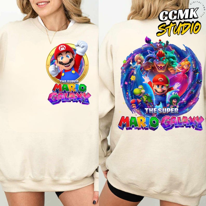 Pode incluir: Camisola creme com um gr&aacute;fico colorido de Mario de "The Super Mario Galaxy". O design frontal mostra Mario num c&iacute;rculo dourado, enquanto a parte de tr&aacute;s apresenta v&aacute;rios personagens. O texto "THE SUPER MARIO GALAXY" &eacute; impresso em ambos os lados.