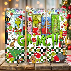 Puede incluir: Un vaso de acero inoxidable con un diseño festivo del Grinch. El vaso muestra al Grinch en varias escenas navideñas, con las palabras "THE GRINCH" en letras verdes grandes. El diseño incluye un árbol de Navidad, regalos y otros elementos navideños.